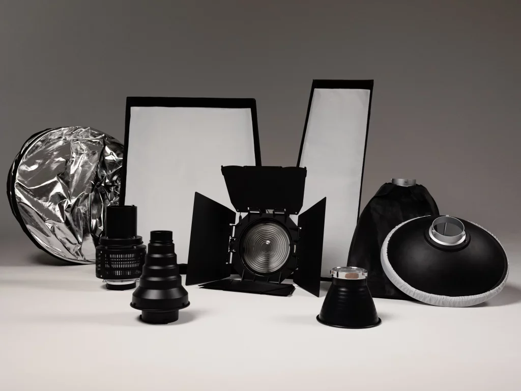 Verschiedene Studio-Lichtformer und -Aufsätze (Reflektor, Softboxen, Barn Doors, Snoots, Beauty Dish) auf neutralem Hintergrund.